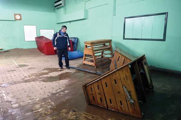 Derek Kay co headteacher at Trinity School, inspects the damage inside the school gym.  Floodwater has lifted gym’s floor