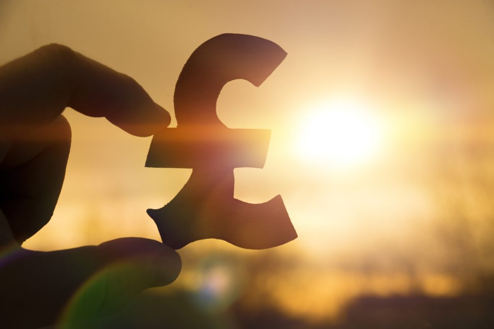 silhouette symbol of the British pound sterling in hand against | Schools Week