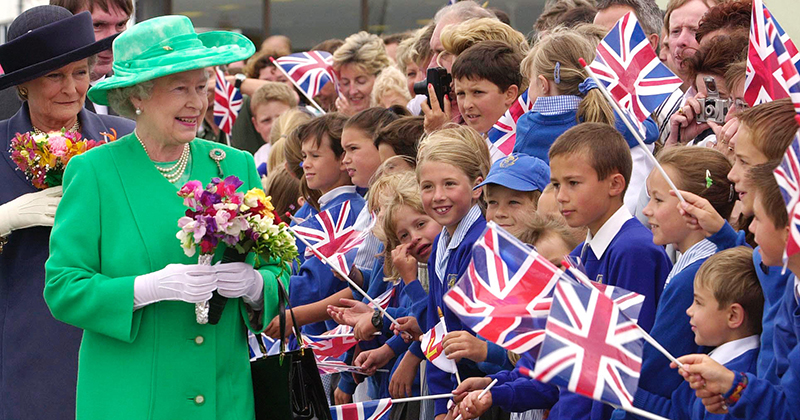 Queen Elizabeth II is greeted by schoolchildren at Guernsey Airport at the start of a two day state visit to the Channel Islands